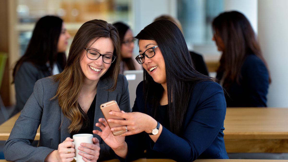 Two women looking at a phone and smiling