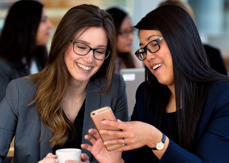 Two women looking at a phone and smiling