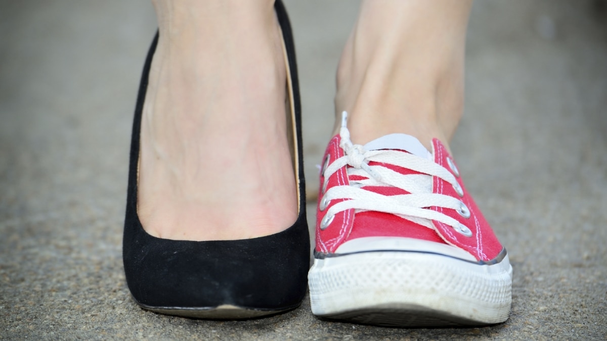 Female feet wearing one red converse and one black high heel