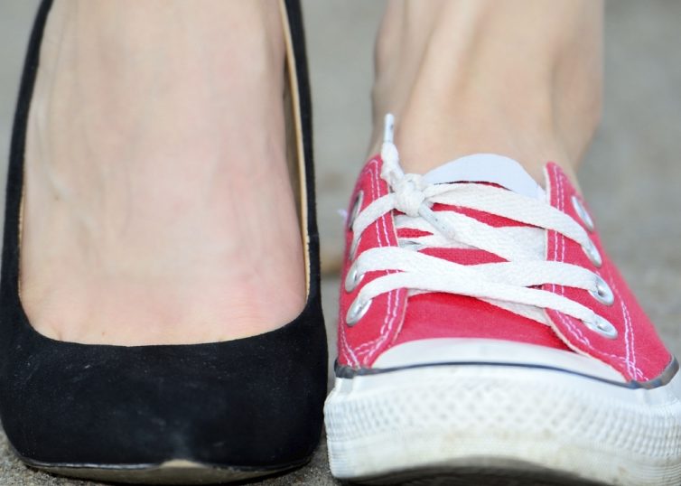 Female feet wearing one red converse and one black high heel
