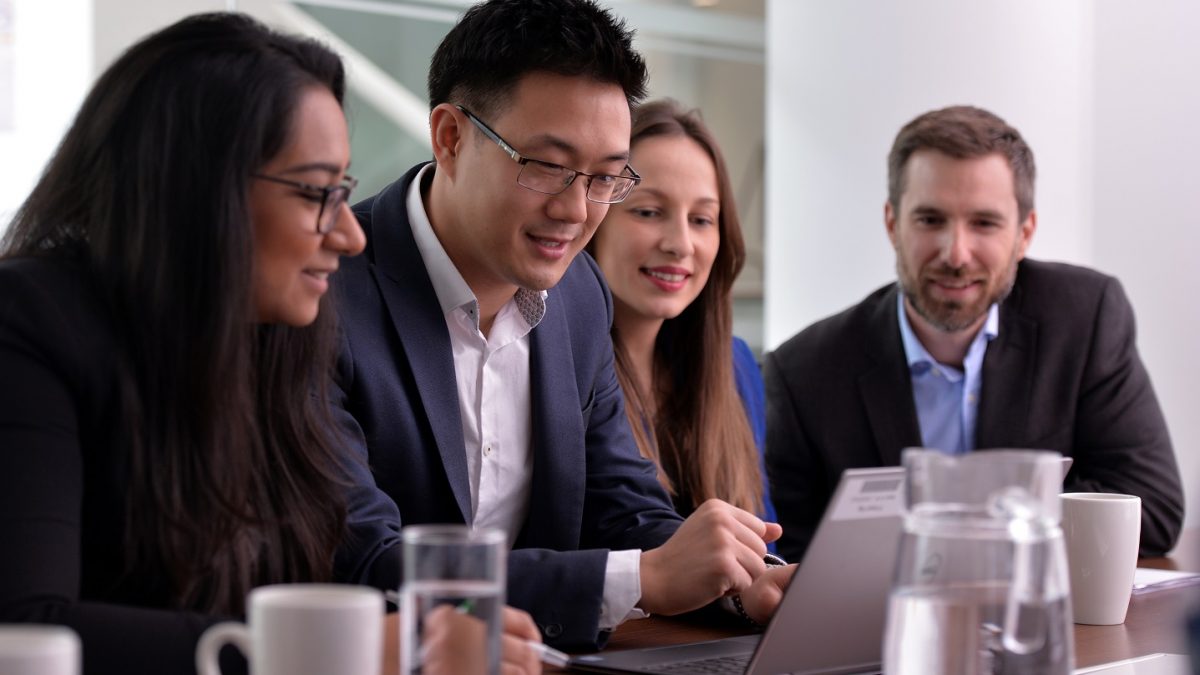 People in professional clothes gathered around a laptop