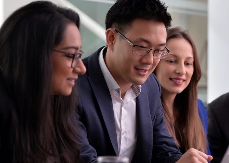 People in professional clothes gathered around a laptop
