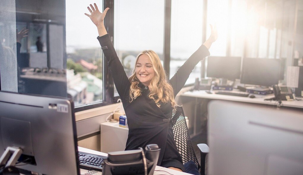Girl throwing her hands in the air in excitement at a desk