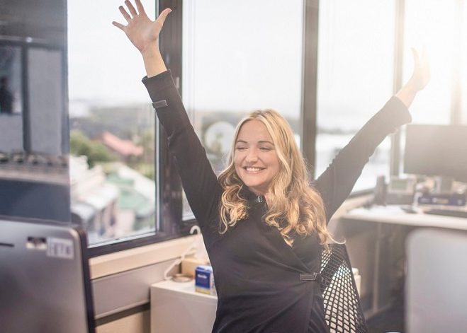 Girl throwing her hands in the air in excitement at a desk