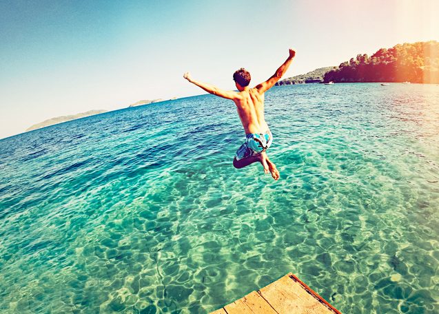 Boy jumping off a dock into the ocean
