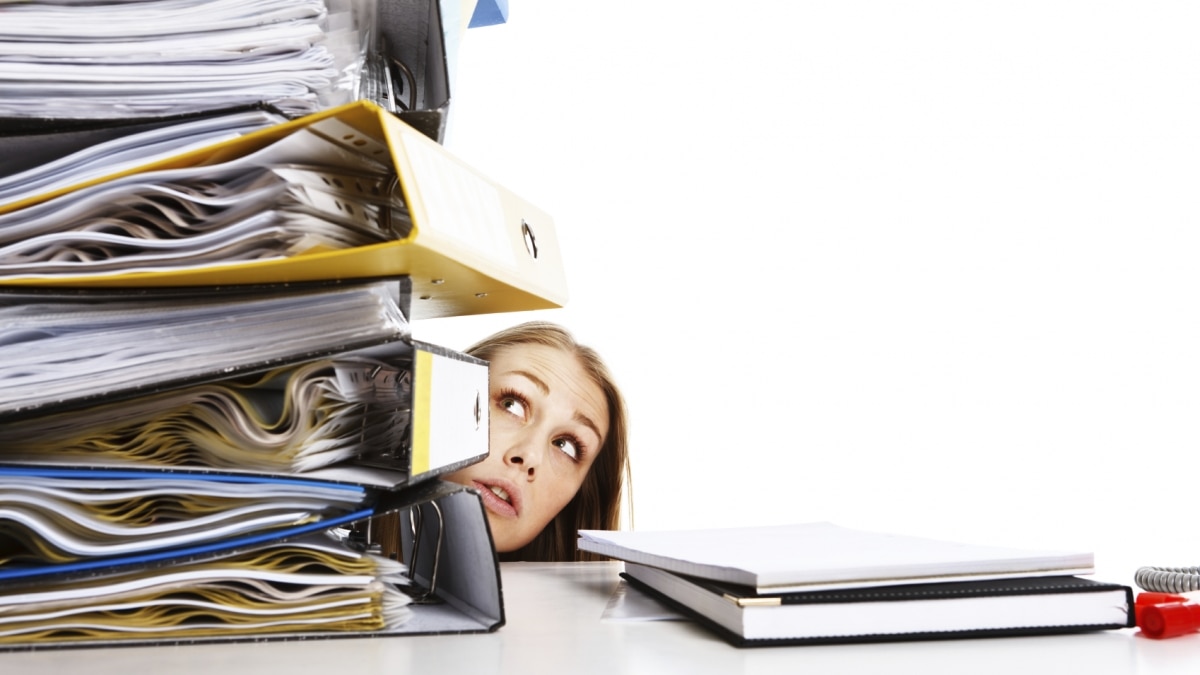 Girl looking concerned at huge stack of binders