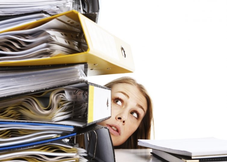 Girl looking concerned at huge stack of binders