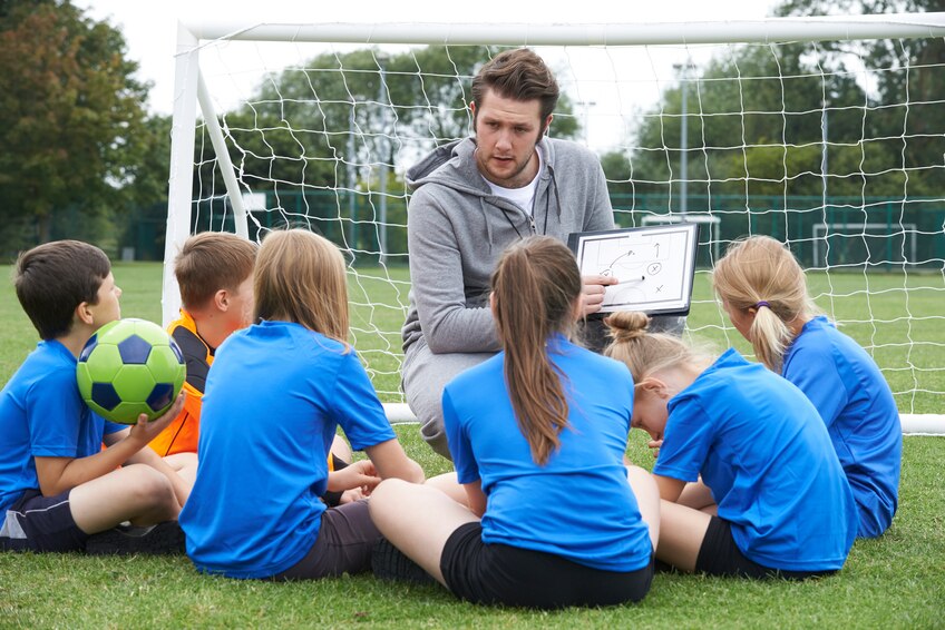 Man showing little kids a soccer strategy