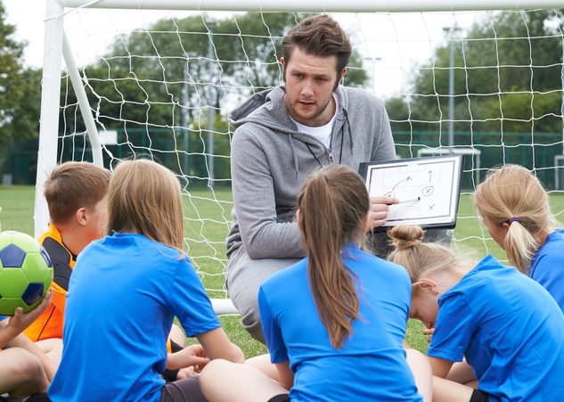 Man showing little kids a soccer strategy