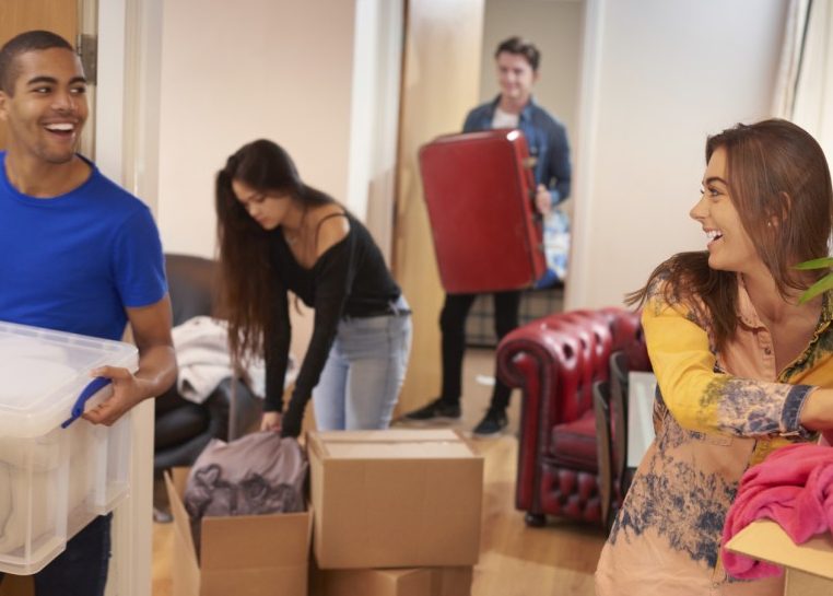 People moving boxes and totes into an apartment