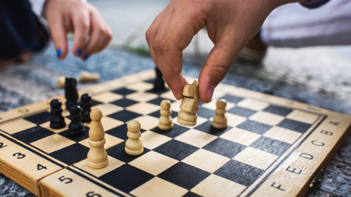 Chess board with hands reaching to move pieces