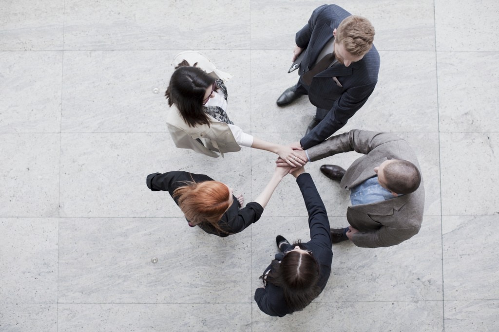 People in suits standing in a circle with their hands in the middle