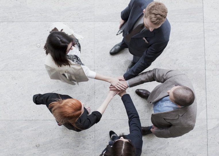 People in suits standing in a circle with their hands in the middle
