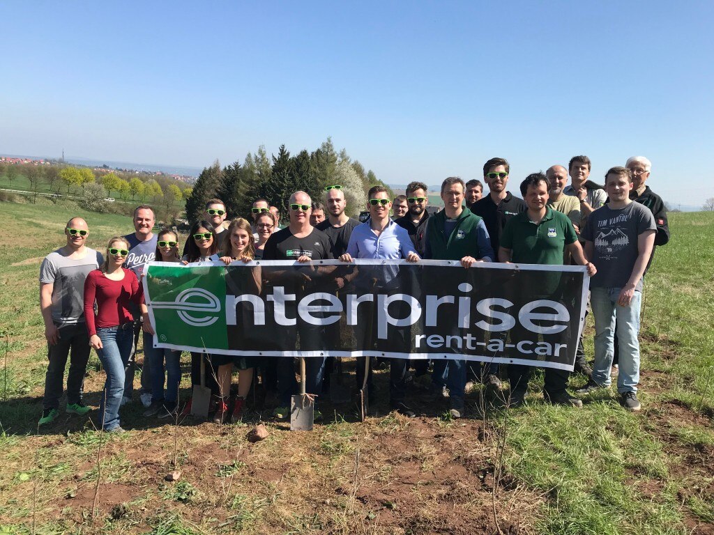 Enterprise Employees with shovels holding an Enterprise banner in a forest
