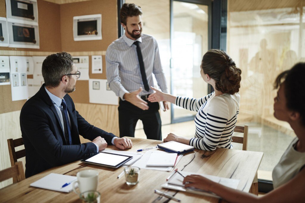 Man shaking hands with people sitting at a table