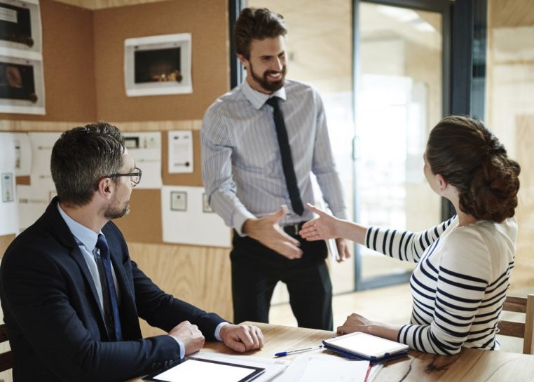 Man shaking hands with people sitting at a table
