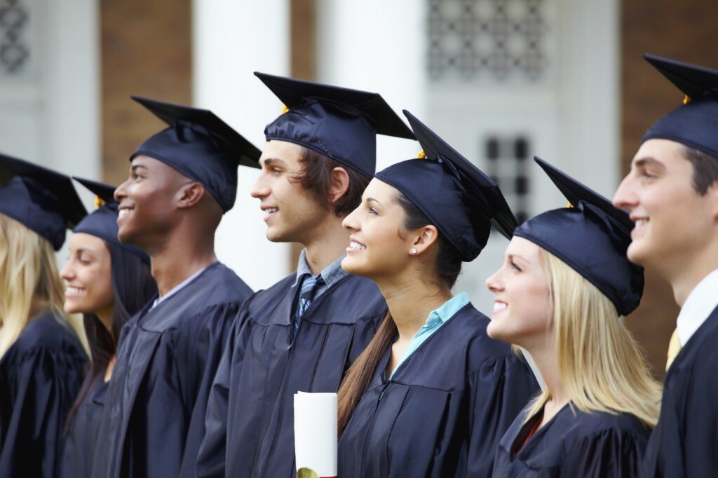 Students in graduation caps and gowns smiling