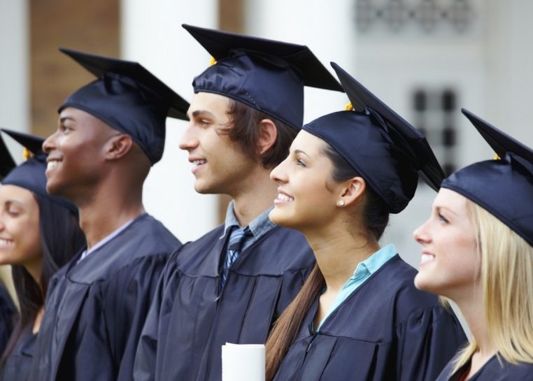 Students in graduation caps and gowns smiling