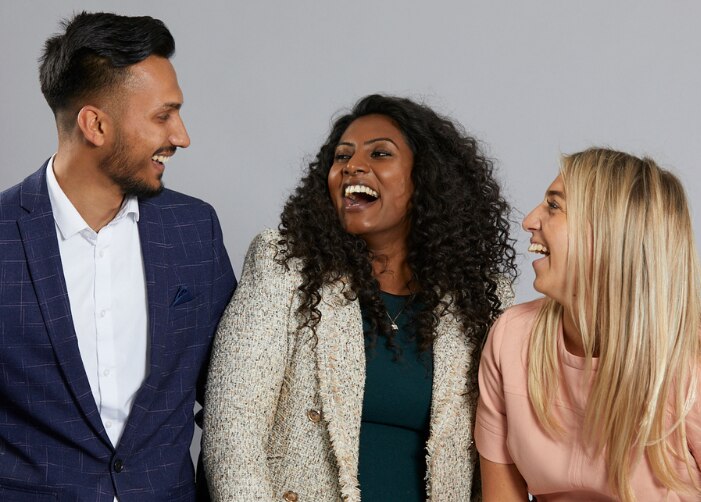 Three people smiling at each other