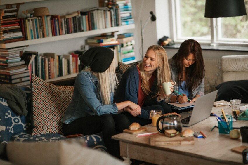 Three girls sitting on a couch together laughing and talking