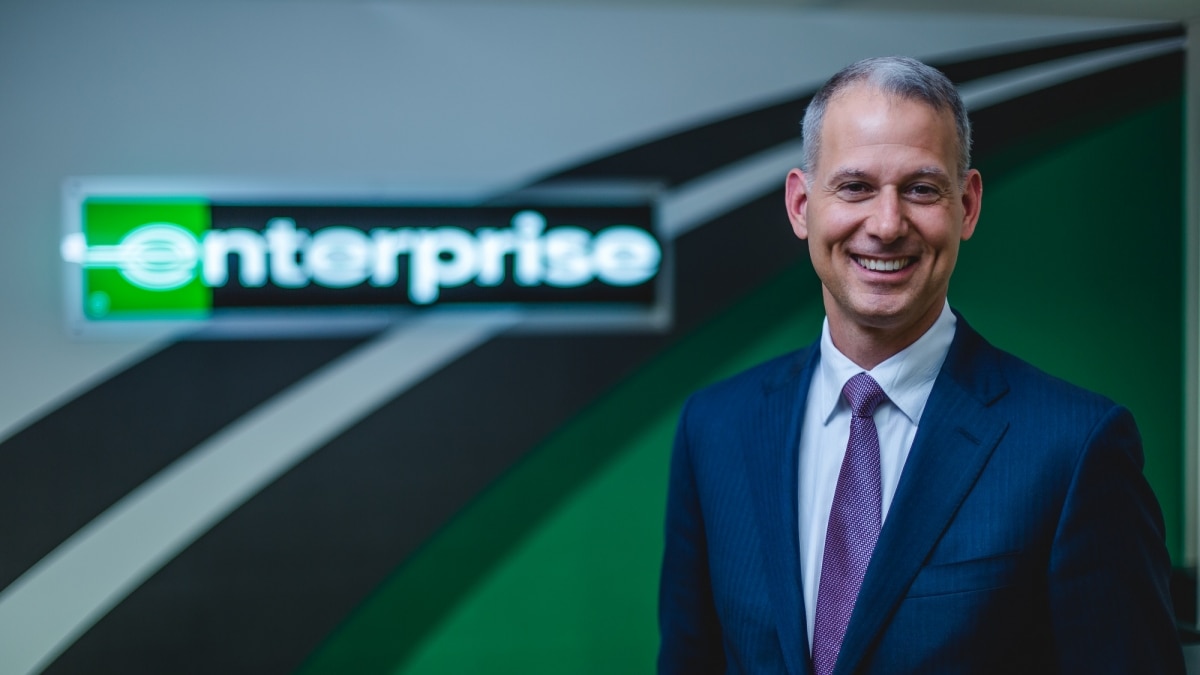 Professional photo of a man in a suit and tie in front of Enterprise signage