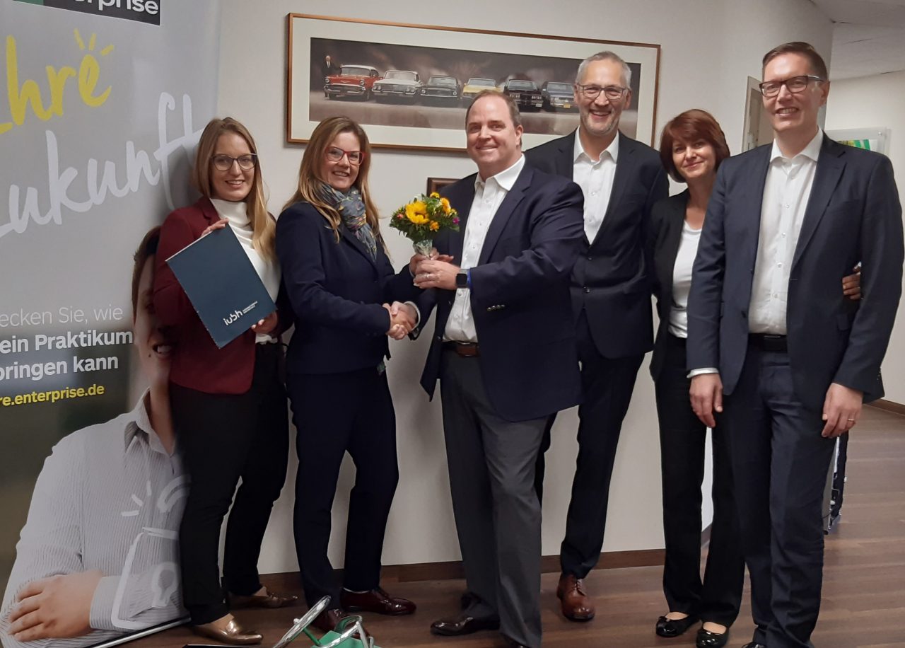 Employees in suits with flowers and a small car