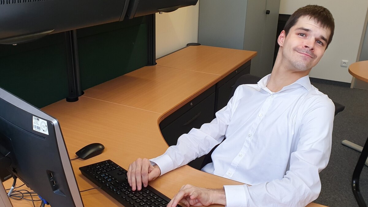 Man in white dress shirt sitting at a desk with a computer