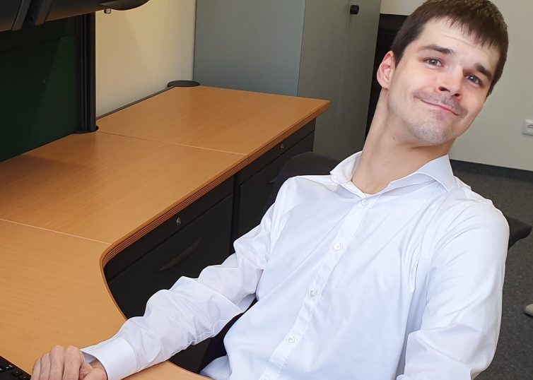 Man in white dress shirt sitting at a desk with a computer
