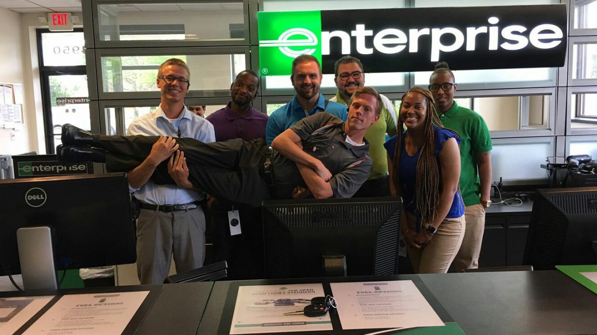 Enterprise Employees behind the front desk holding up one employee