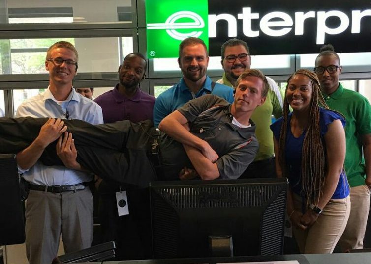 Enterprise Employees behind the front desk holding up one employee