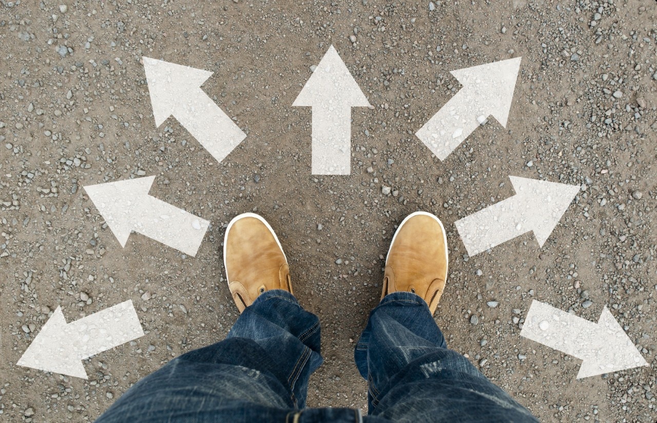 Feet on pavement with arrows painted in different directions