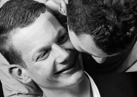 A man in a suit being embraced by another man from behind
