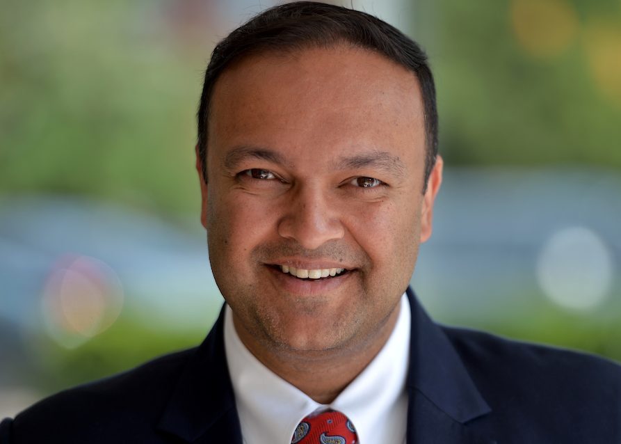 Photo of man in suit with a red tie with blurred background