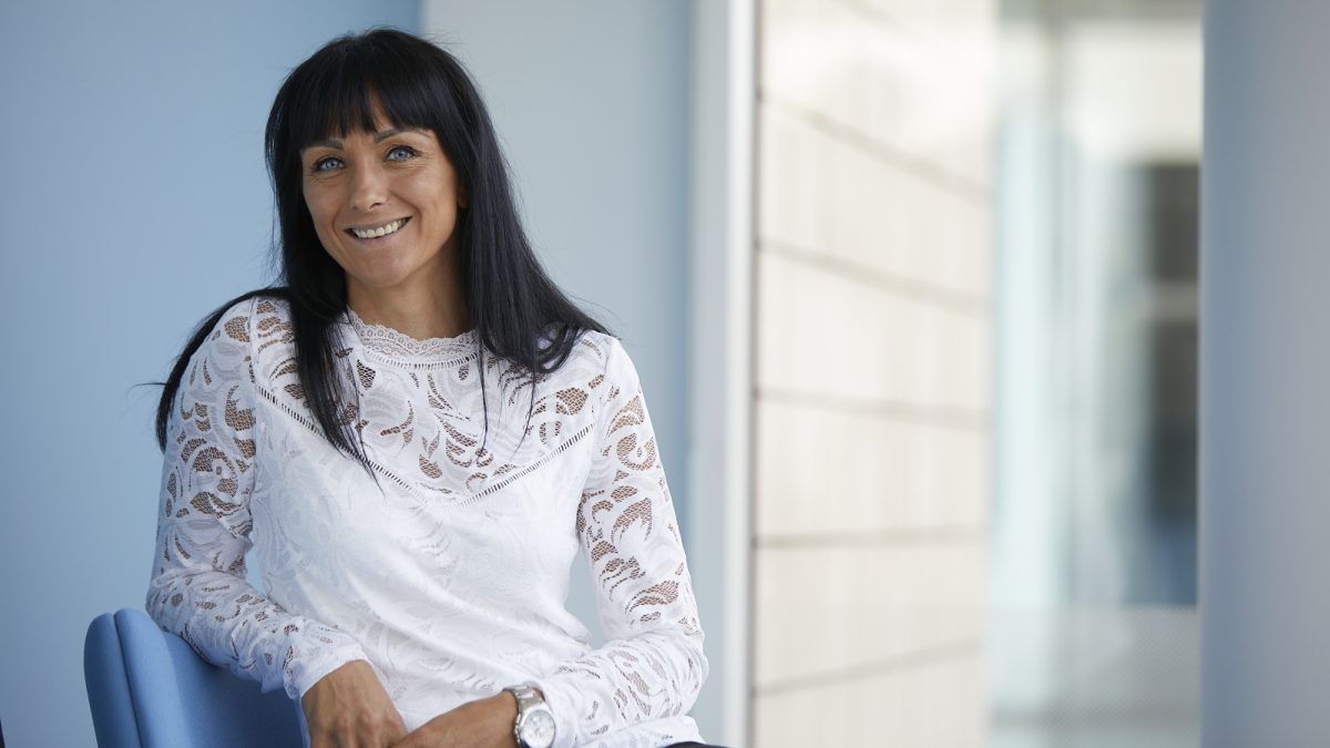 Lady in a white blouse sitting in a chair and smiling