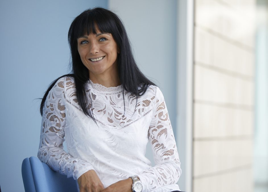 Lady in a white blouse sitting in a chair and smiling