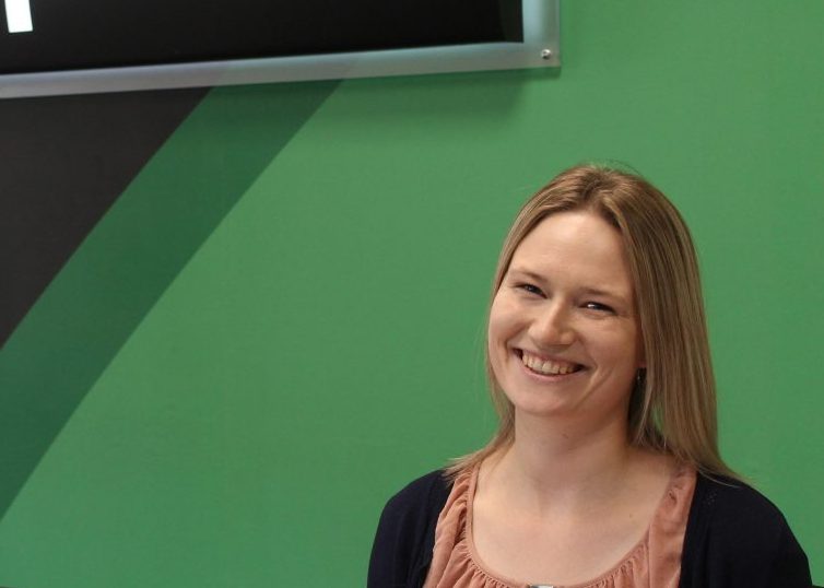 Woman smiling in front of Enterprise sign on a green wall