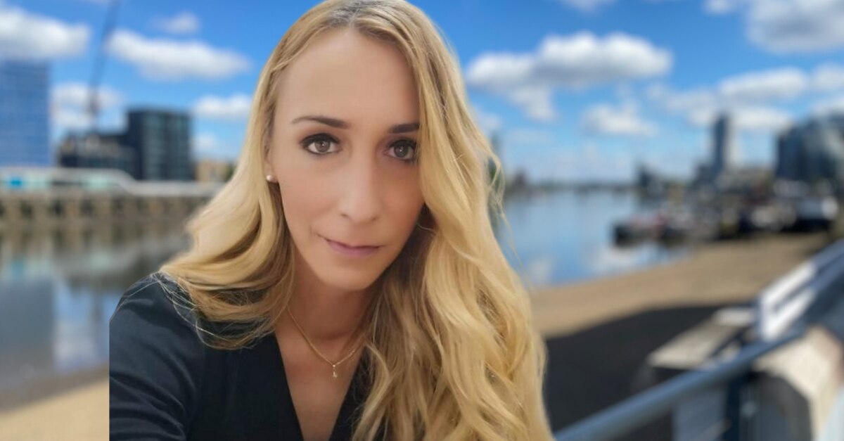 Woman with long blonde hair in front of river and city