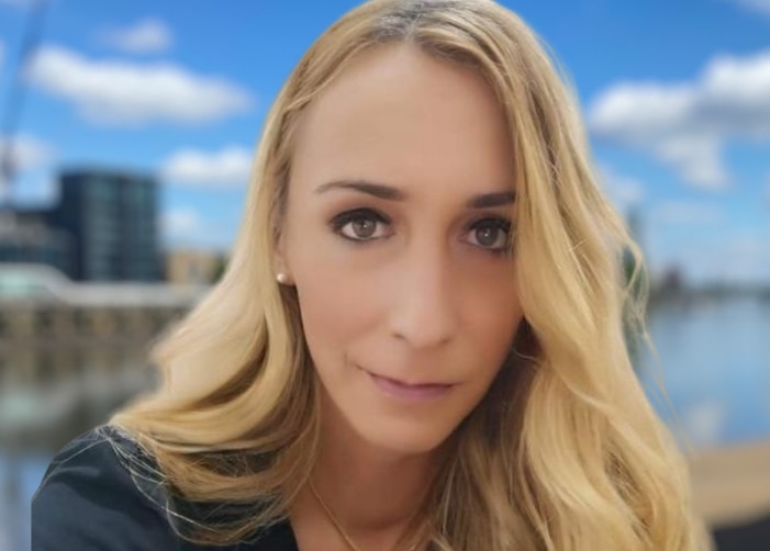 Woman with long blonde hair in front of river and city