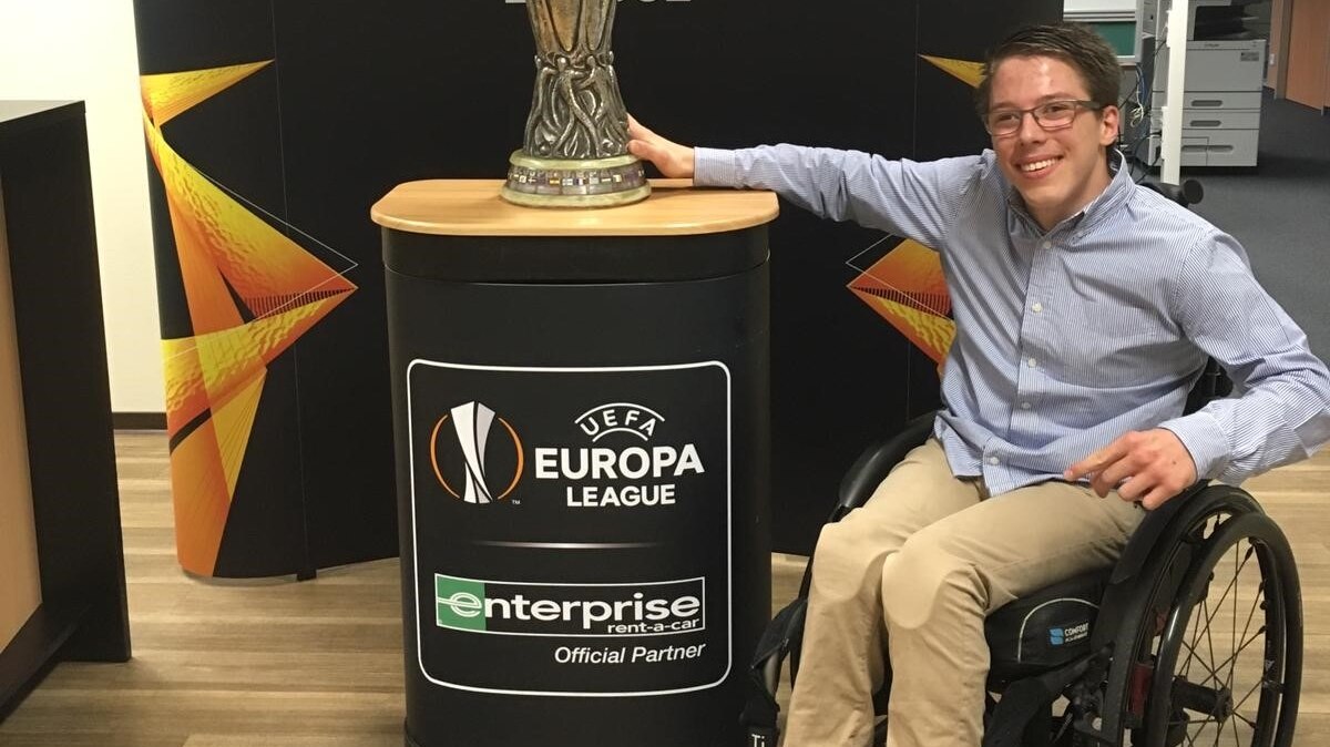 Man in wheelchair posing next to a trophy