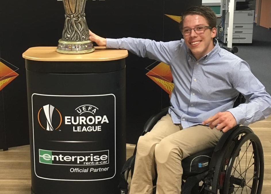 Man in wheelchair posing next to a trophy