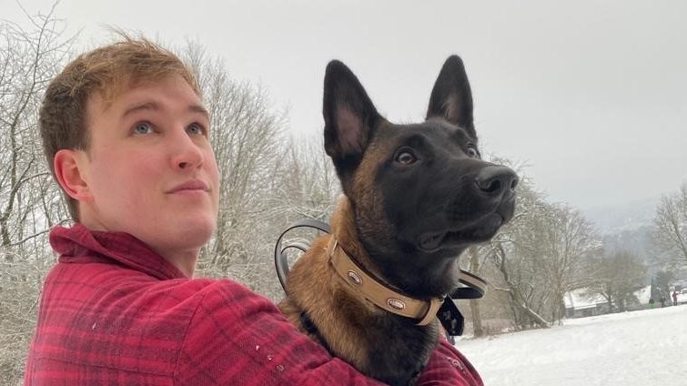 Man holding a dog and looking into the distance