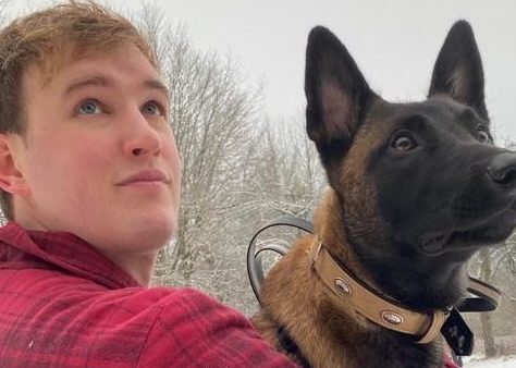 Man holding a dog and looking into the distance