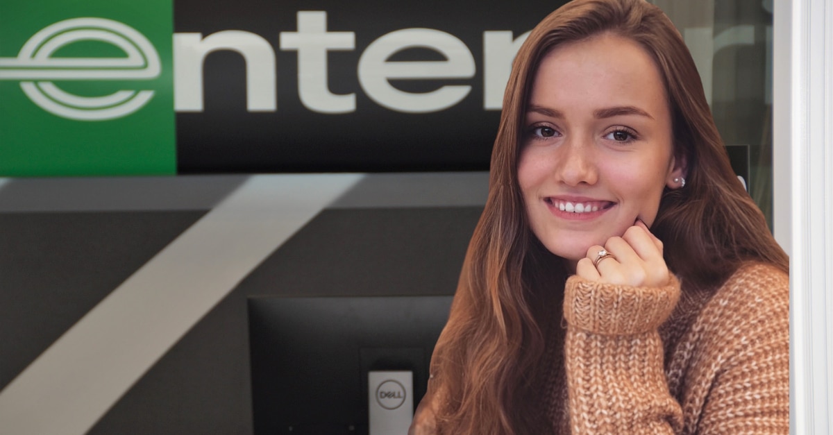 Photo of a girl in a sweater in front of Enterprise sign