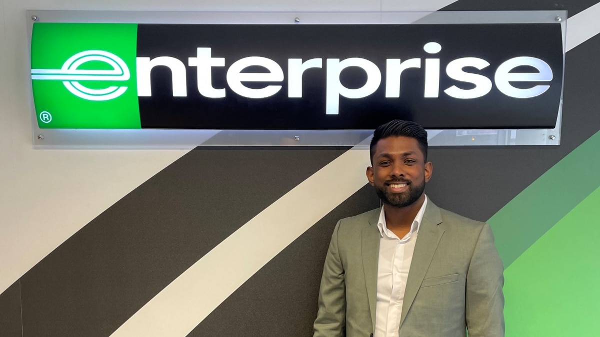 Man in suit in front of Enterprise sign