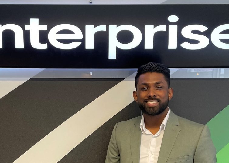 Man in suit in front of Enterprise sign