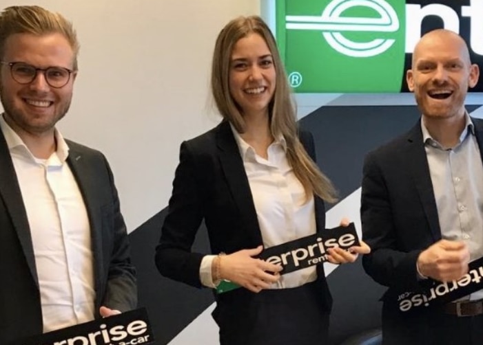 3 Enterprise employees pretending to play Enterprise signs as guitars