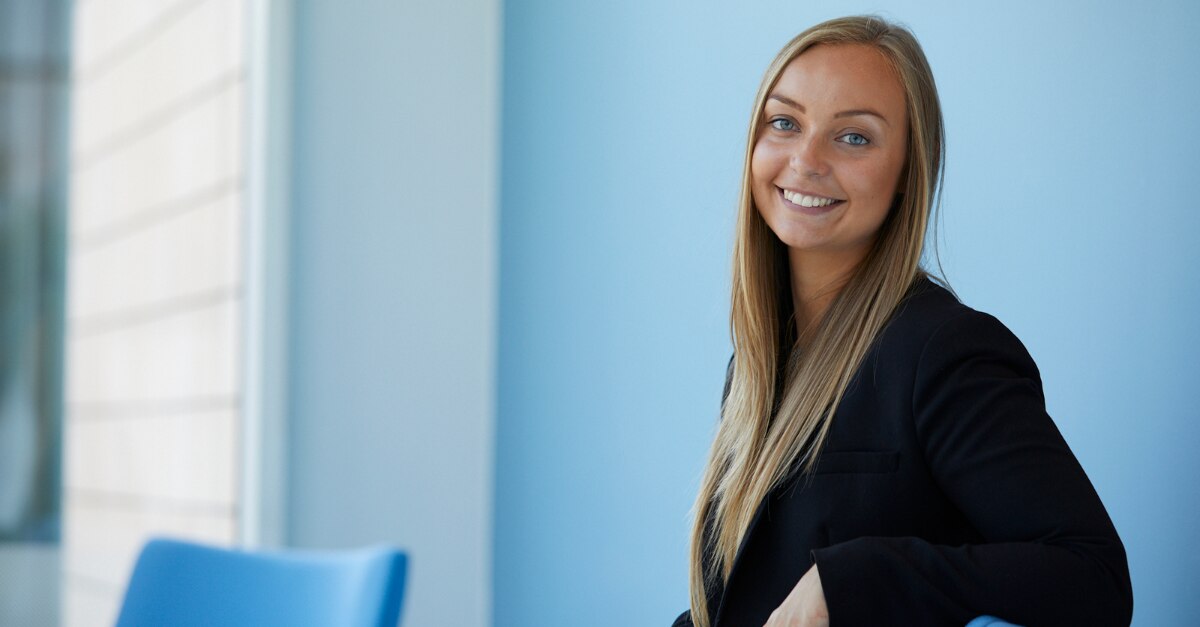 Professional picture of a girl sitting in front of a blue wall next to a blue chair