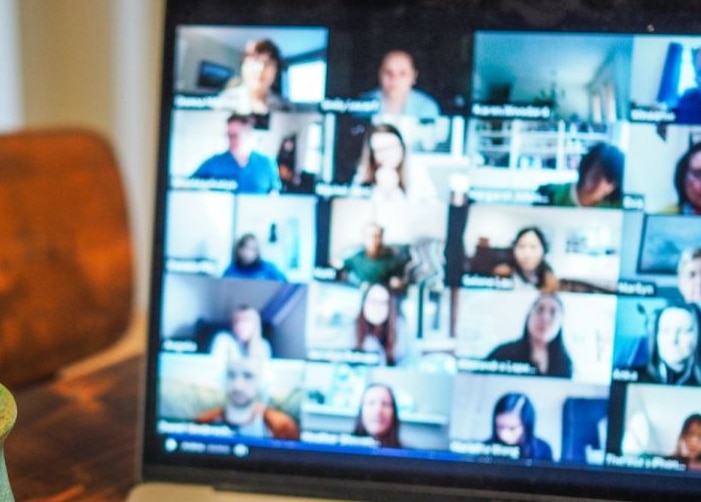 Open Macbook with Zoom meeting on screen sitting on table next to green mug