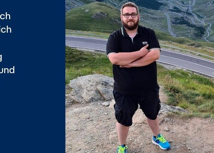 Man standing with his arms crossed on rocks above a highway