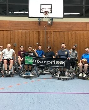 Wheelchair basektball players with Enterprise banner